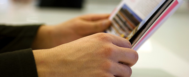 Person Reading The Benefits Of Digital Signage In A Magazine - 4-10